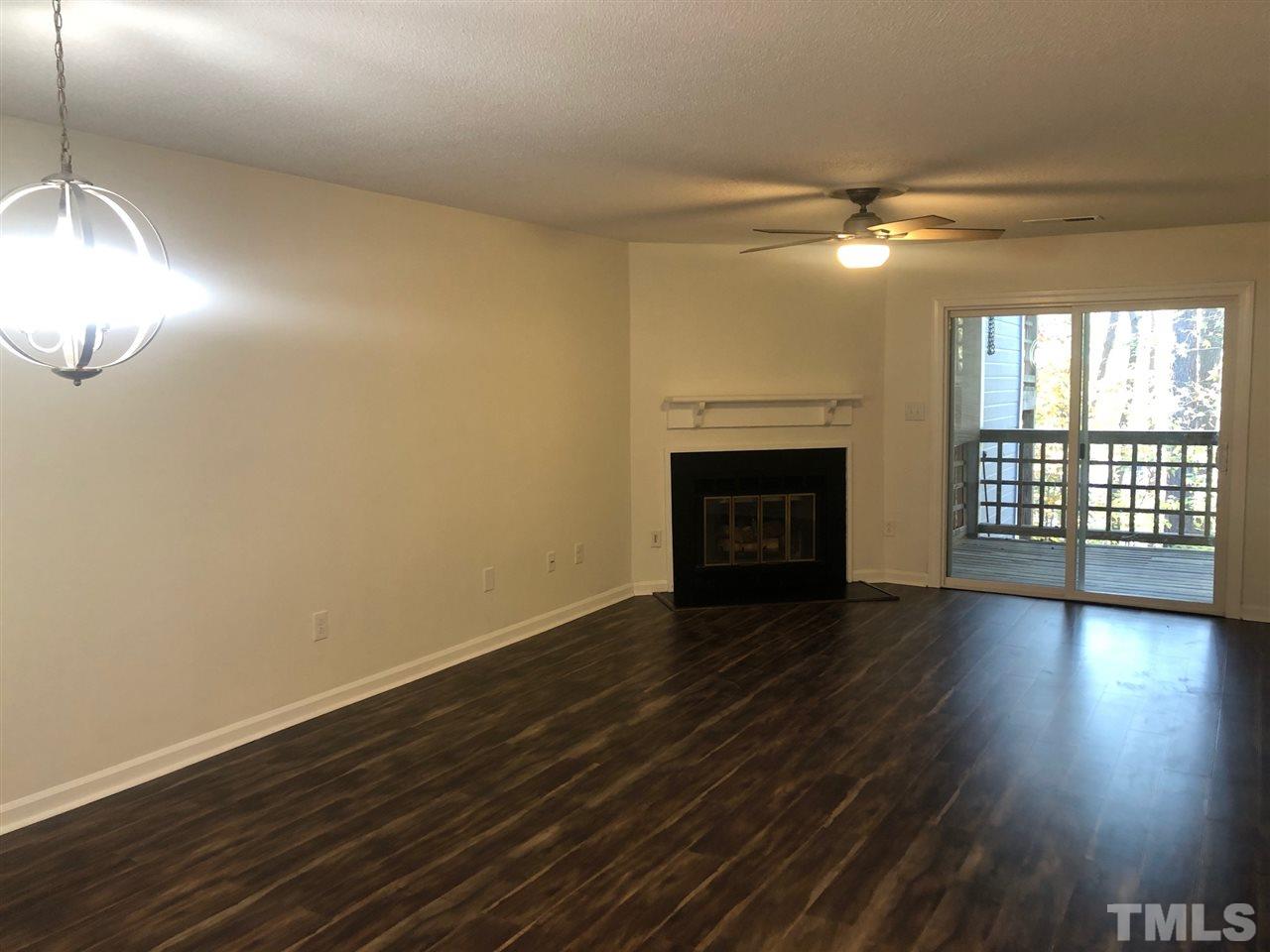 4621 Timbermill Court, Unit 103 Raleigh, NC 27612 - Photo 5 of 13 an empty room with wooden floor fireplace and windows