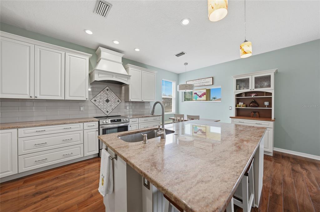 5221 Layton Drive Venice, FL 34293 - Photo 12 of 33 a kitchen with granite countertop a stove a sink dishwasher and cabinets with wooden floor