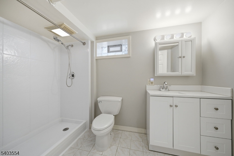 52 Broadway Clark, NJ 07066 - Photo 32 of 47 a bathroom with a toilet a sink a mirror and vanity