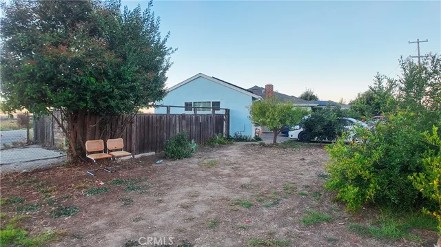 a view of a backyard with large trees and wooden fence