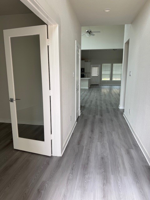 7838 Ruth Ravine Court Spring, TX 77379 - Photo 2 of 23 This photo shows a bright hallway with light gray flooring, leading to an open living area with large windows and a ceiling fan. A glass-paneled door to the left suggests a separate room or office space.