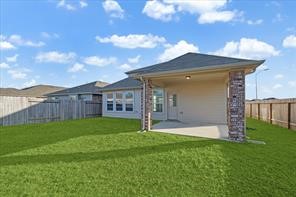 7838 Ruth Ravine Court Spring, TX 77379 - Photo 22 of 23 This photo showcases a backyard with lush green grass and a covered patio area attached to the house, offering a cozy outdoor space. The yard is enclosed by a wooden fence, providing privacy.
