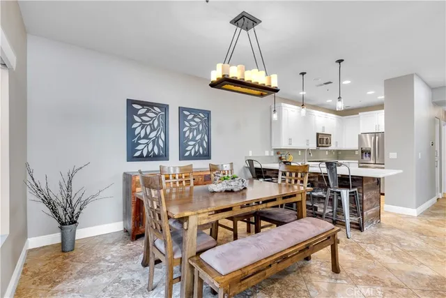 a view of a dining room and livingroom with furniture wooden floor a rug a painting and a chandelier