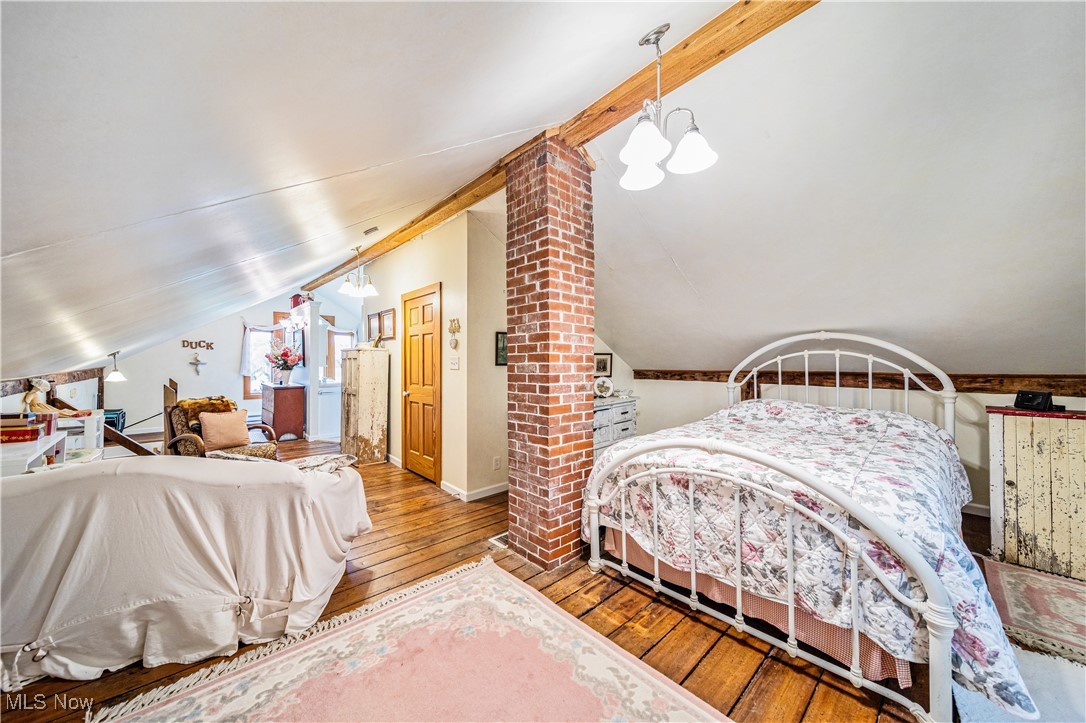 4804 Guest Road Jefferson, OH 44047 - Photo 23 of 48 Bedroom featuring an inviting chandelier, light wood-type flooring, lofted ceiling, and decorative columns