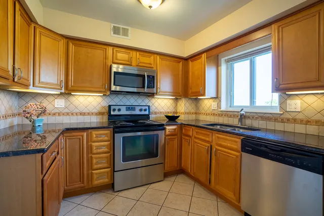 a kitchen with stainless steel appliances granite countertop a stove sink microwave and refrigerator