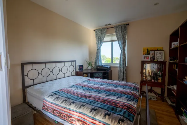 a bedroom with a bed a large window and book shelf