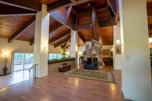 an empty room with wooden floor fireplace and windows