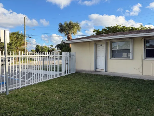 a view of a house with a small yard and wooden fence