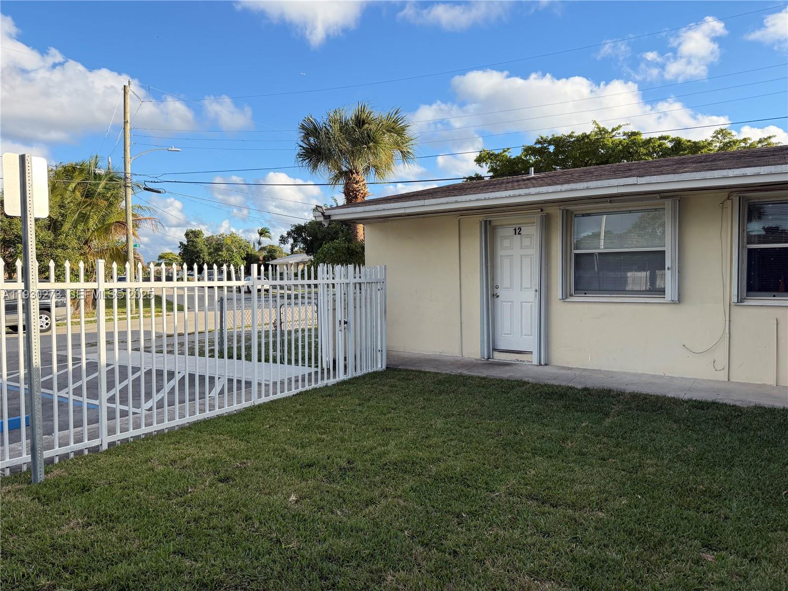 a view of a house with a small yard and wooden fence