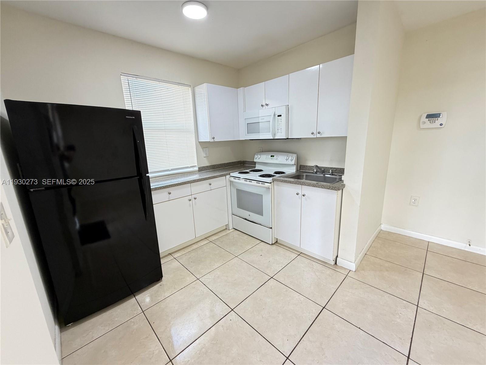 609 Northwest 7th Avenue, Unit 12 Hallandale Beach, FL 33009 - Photo 11 of 18 a kitchen with a sink a refrigerator and cabinets