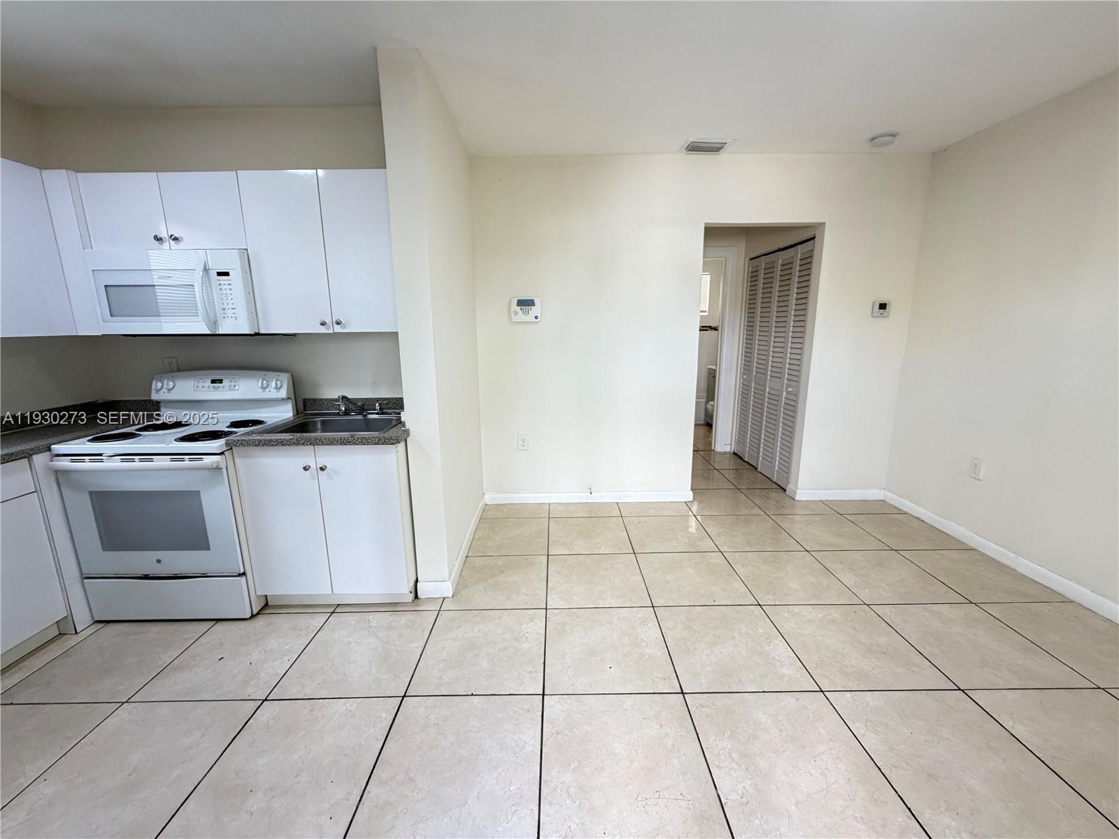609 Northwest 7th Avenue, Unit 12 Hallandale Beach, FL 33009 - Photo 13 of 18 a kitchen with a stove a sink and a refrigerator