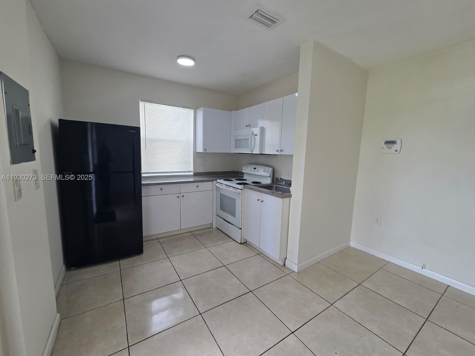 609 Northwest 7th Avenue, Unit 12 Hallandale Beach, FL 33009 - Photo 2 of 18 a kitchen with a refrigerator a stove top oven and cabinets