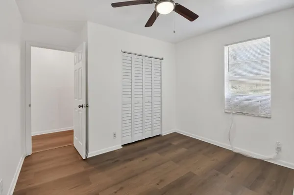 an empty room with wooden floor cabinet and windows