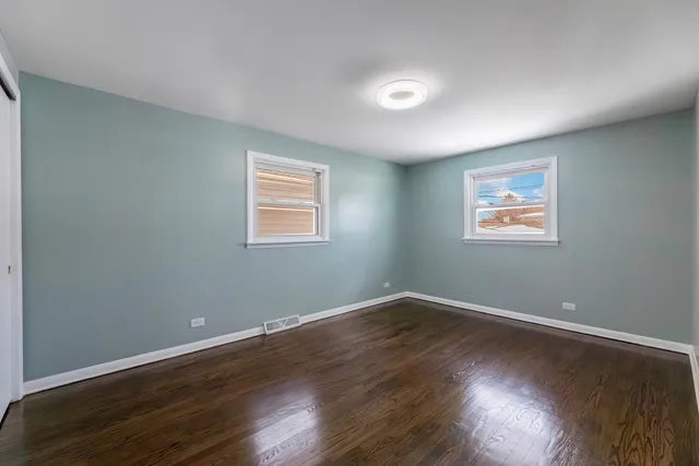 a view of a big room with wooden floor and windows