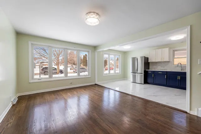 a large living room with stainless steel appliances wooden floors and large window
