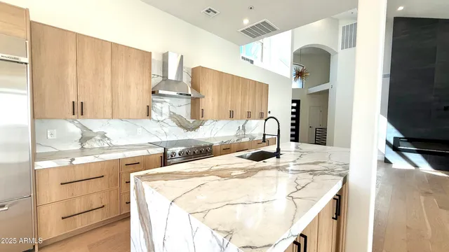 a kitchen with kitchen island granite countertop a sink cabinets and stainless steel appliances