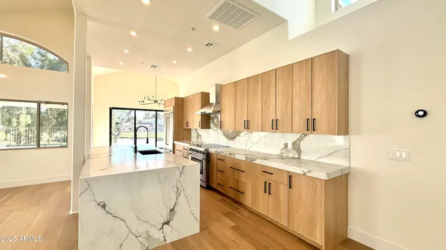 a kitchen with stainless steel appliances kitchen island granite countertop a stove a refrigerator a sink and a wooden floors