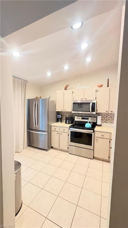 4120 Looking Glass Lane, Unit 3708 Naples, FL 34112 - Photo 13 of 25 Kitchen with appliances with stainless steel finishes, light countertops, backsplash, light tile patterned floors, and white cabinetry