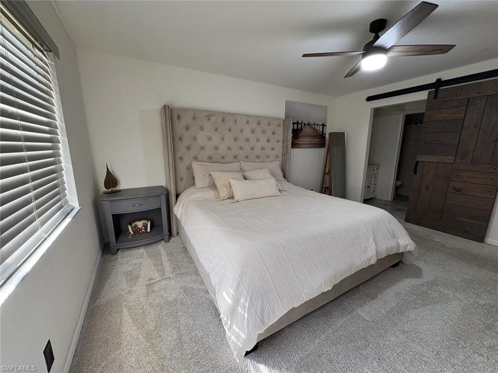 4120 Looking Glass Lane, Unit 3708 Naples, FL 34112 - Photo 15 of 25 Carpeted bedroom with a barn door, ensuite bath, and a ceiling fan