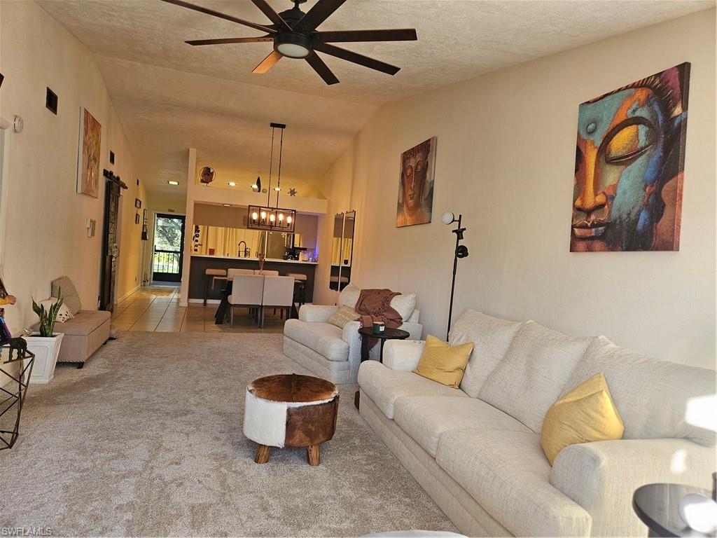 4120 Looking Glass Lane, Unit 3708 Naples, FL 34112 - Photo 4 of 25 Living room with ceiling fan, light carpet, vaulted ceiling, and a textured ceiling