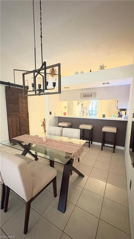 4120 Looking Glass Lane, Unit 3708 Naples, FL 34112 - Photo 10 of 25 Dining room featuring a towering ceiling, light tile patterned floors, a barn door, and a chandelier