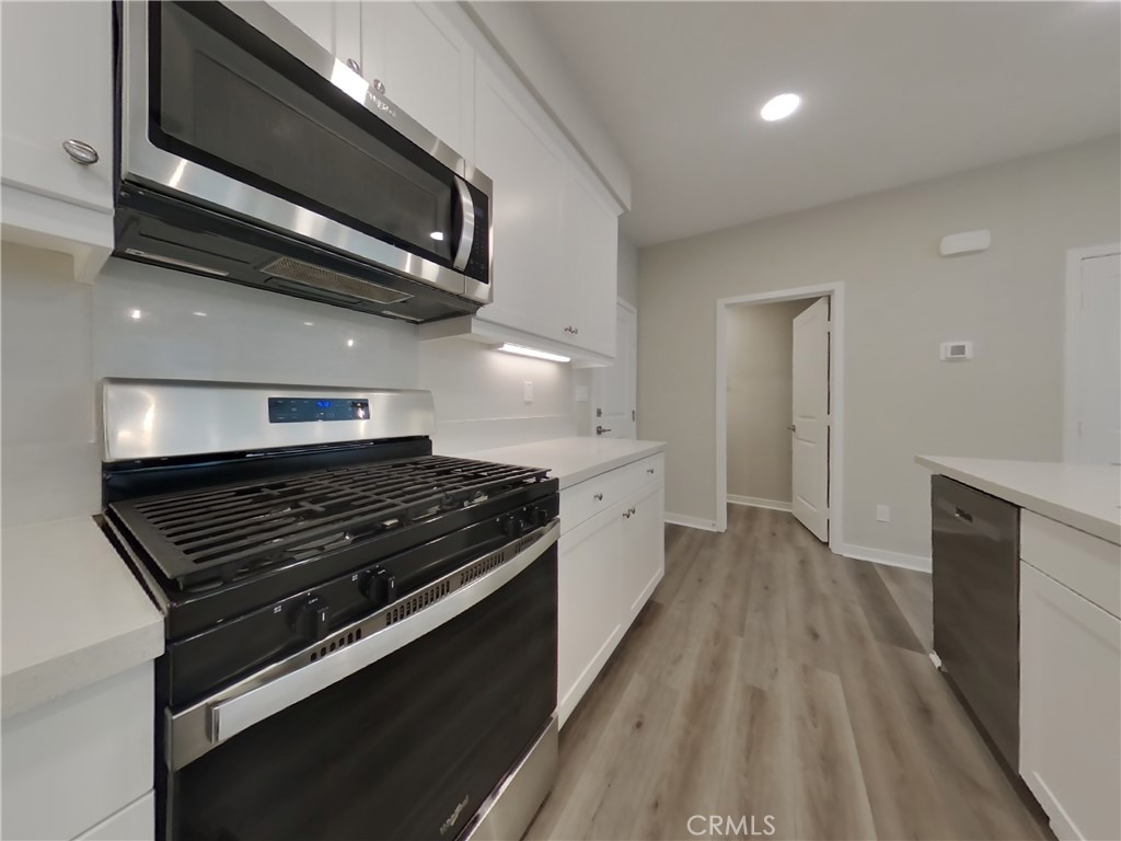 24967 Padre Court Wildomar, CA 92595 - Photo 5 of 30 a kitchen with stainless steel appliances a stove a microwave and cabinets