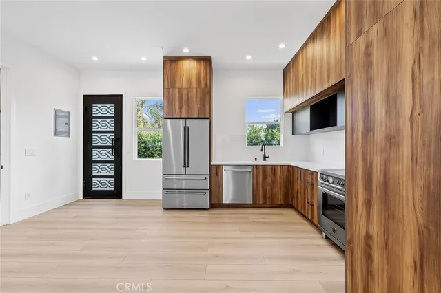 a kitchen with stainless steel appliances kitchen island granite countertop a refrigerator and a stove top oven