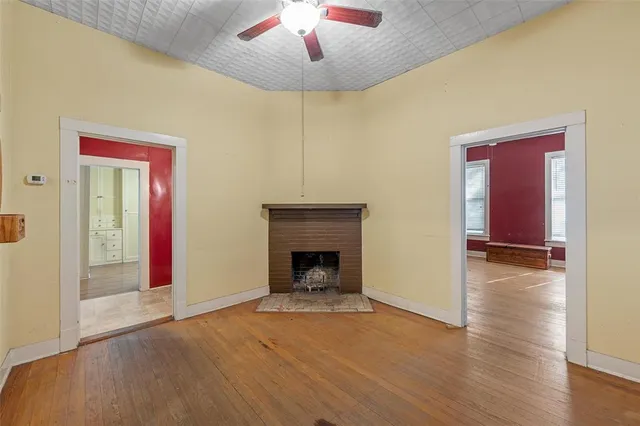 a view of an empty room with wooden floor fireplace and a window