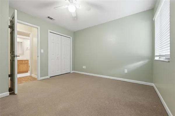 an empty room with a chandelier fan and windows