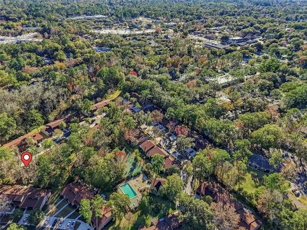an aerial view of residential house with green space and tree in back