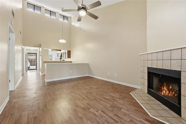 a view of a kitchen and an empty room with wooden floor