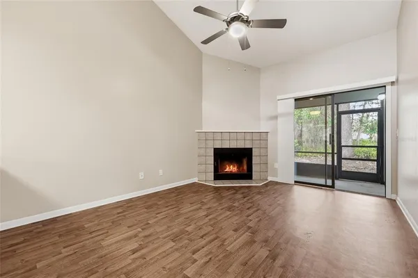 a view of an empty room with wooden floor fireplace and a window