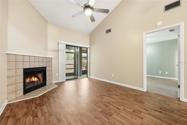 a view of an empty room with wooden floor fireplace and a window