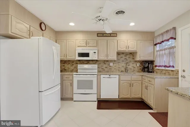 a kitchen with refrigerator a stove and white cabinets