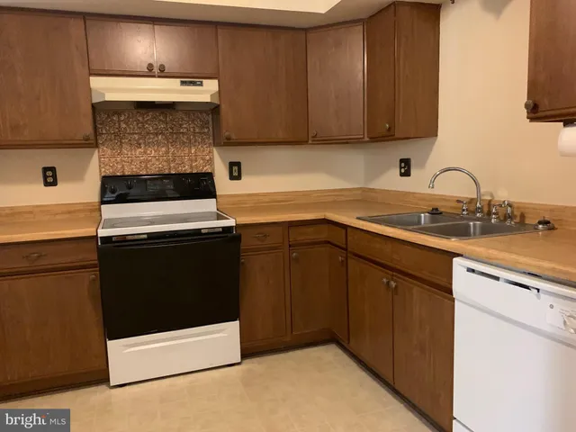 a kitchen with a sink and a stove with wooden floor