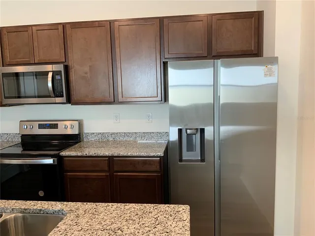 a kitchen with stainless steel appliances granite countertop a refrigerator and a stove