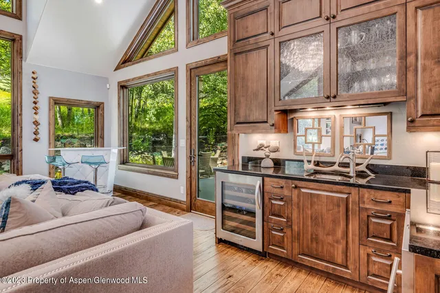 a living room with stainless steel appliances granite countertop furniture a large window and a kitchen