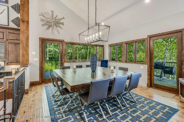 a dining room with wooden floor a chandelier a rug a potted plant and a chandelier