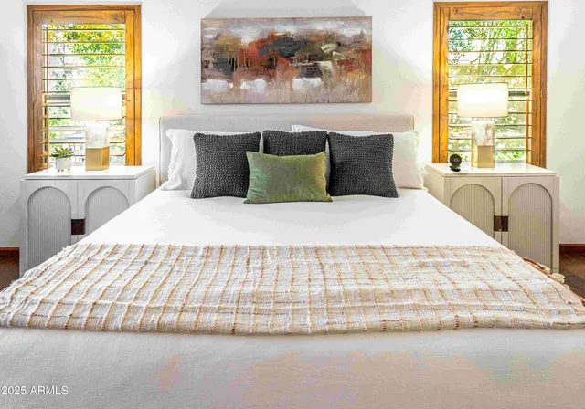 a large white bed sitting in a bedroom next to a window