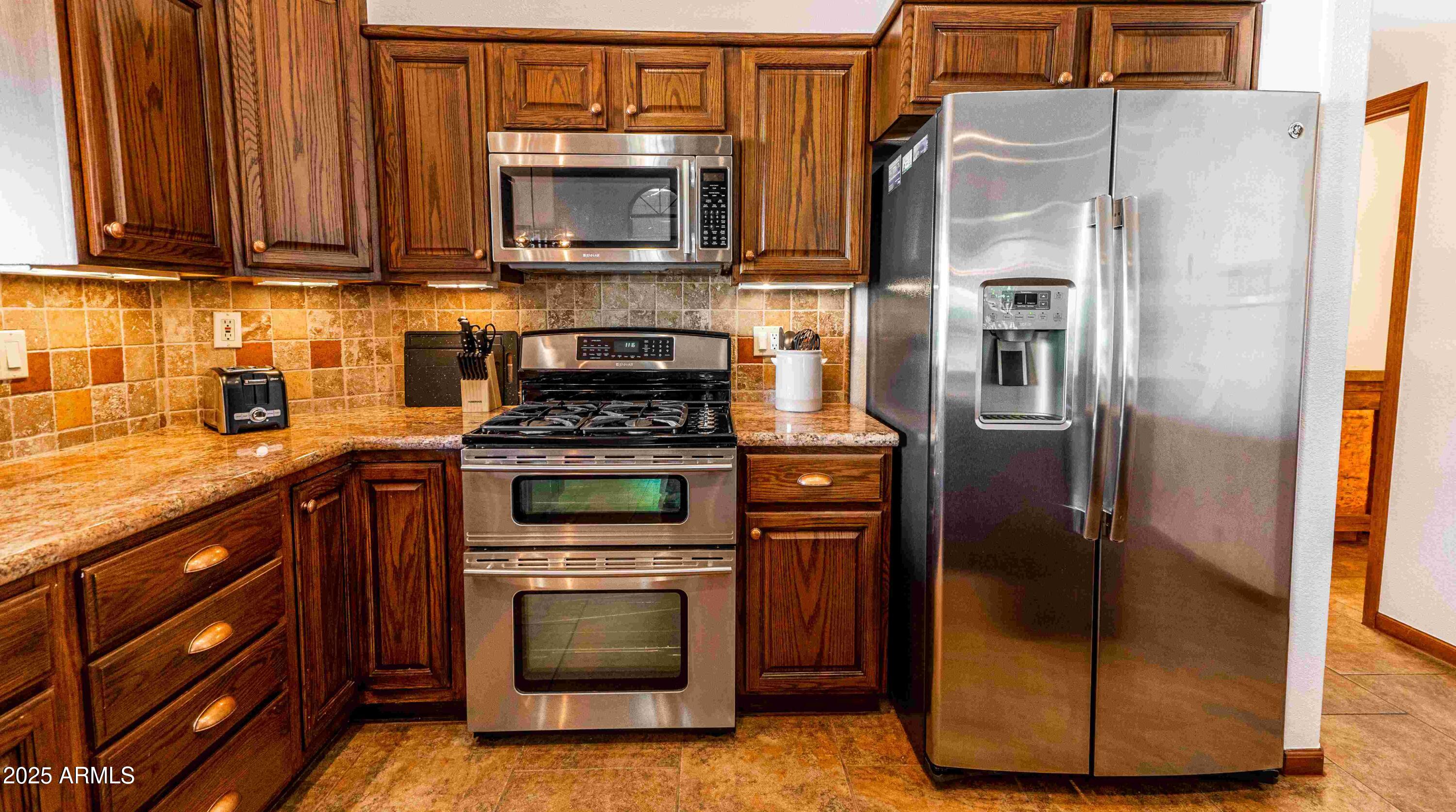 5426 East Libby Street Scottsdale, AZ 85254 - Photo 3 of 29 a kitchen with stainless steel appliances granite countertop a stove a microwave and a refrigerator