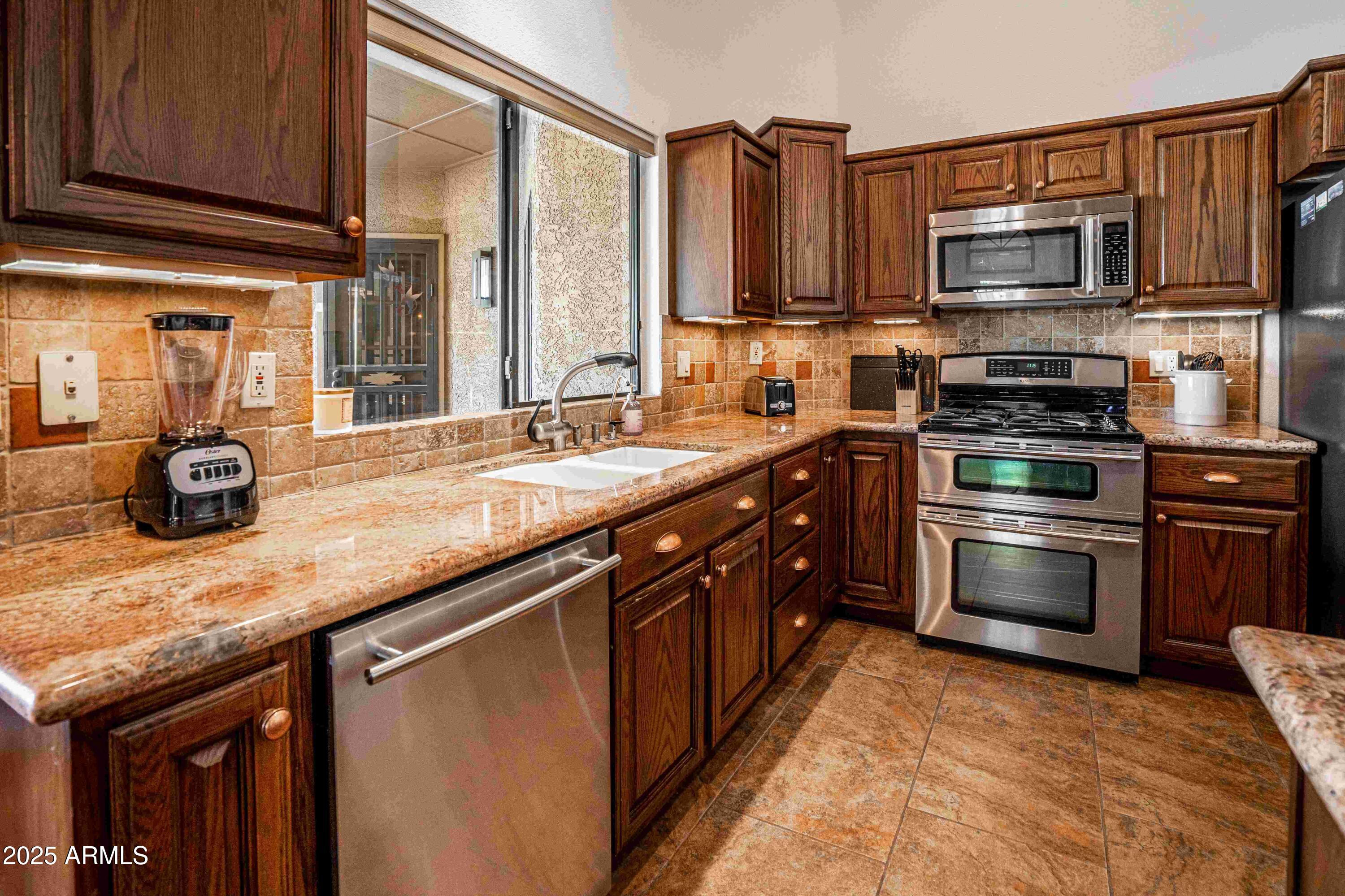 5426 East Libby Street Scottsdale, AZ 85254 - Photo 4 of 29 a kitchen with stainless steel appliances granite countertop a stove a sink and a microwave
