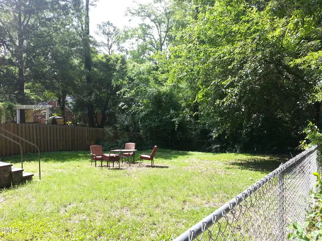 an empty room with wooden floor chandelier fan and windows