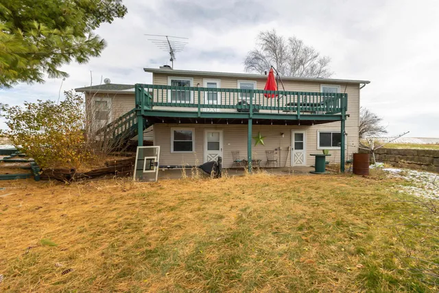 a yellow house with a small yard and large trees