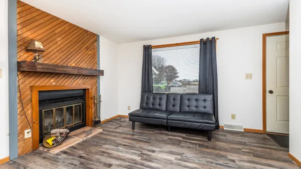 a living room with a fireplace furniture a ceiling fan and a wooden floor