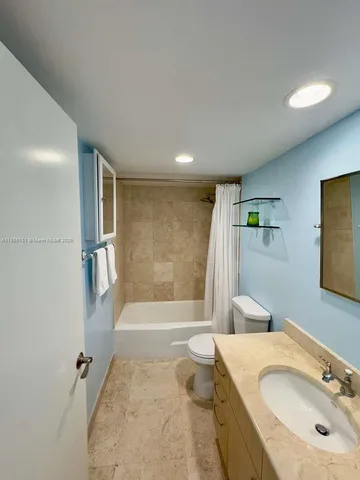 a bathroom with a granite countertop sink a toilet and shower