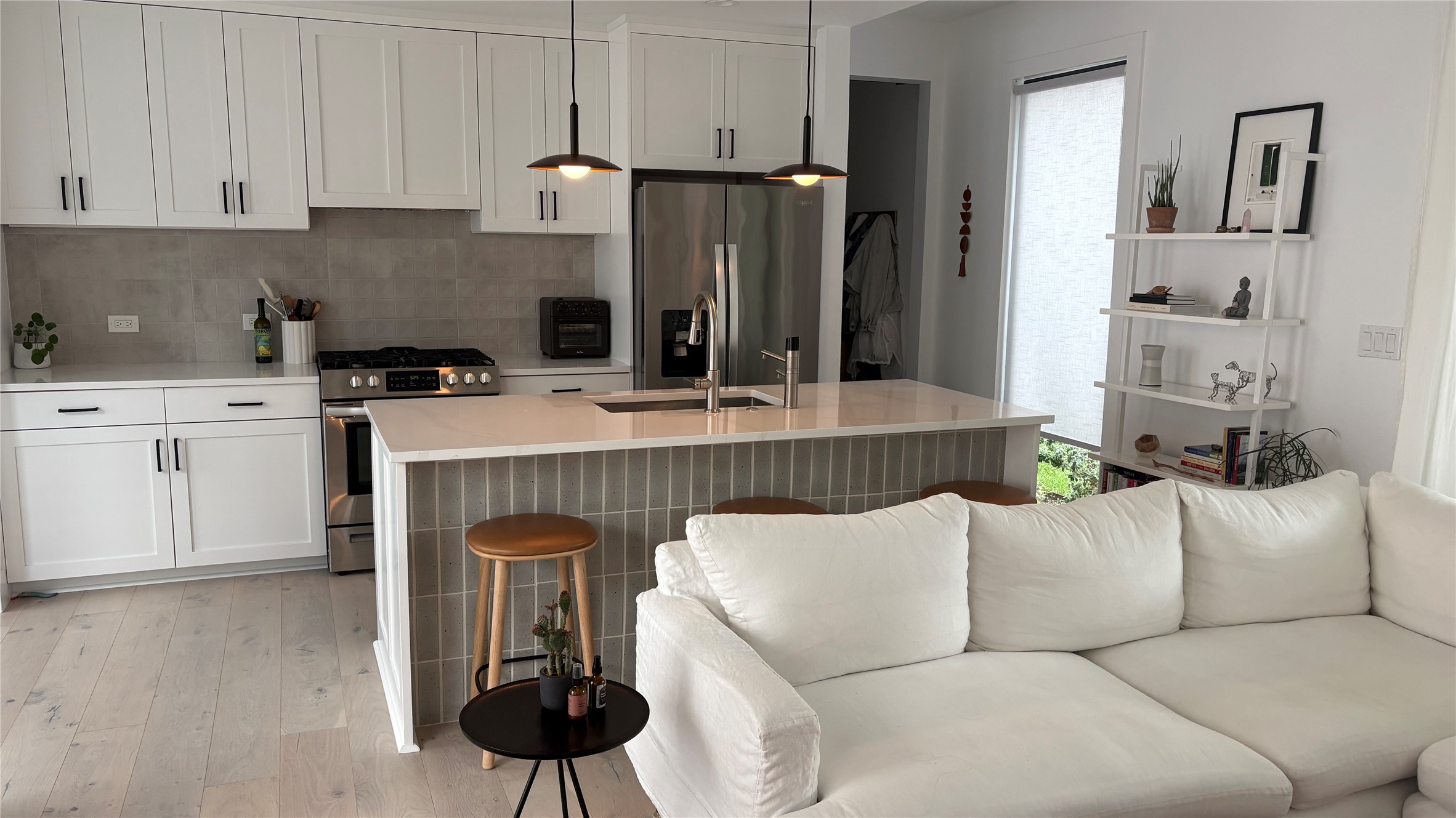 1816 Adina Street, Unit 2 Austin, TX 78721 - Photo 6 of 25 Open-concept kitchen featuring white shaker cabinetry, stainless steel appliances, a light-toned backsplash, and a large island with a tiled face and pendant lighting