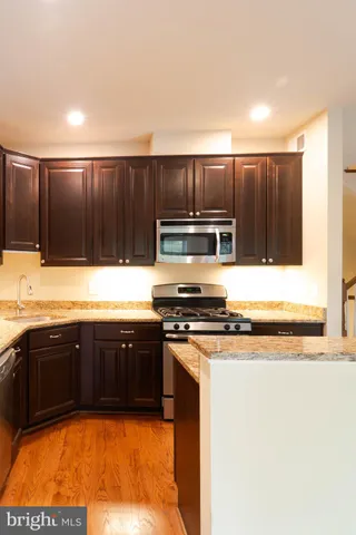 a kitchen with granite countertop wooden cabinets a stove and microwave