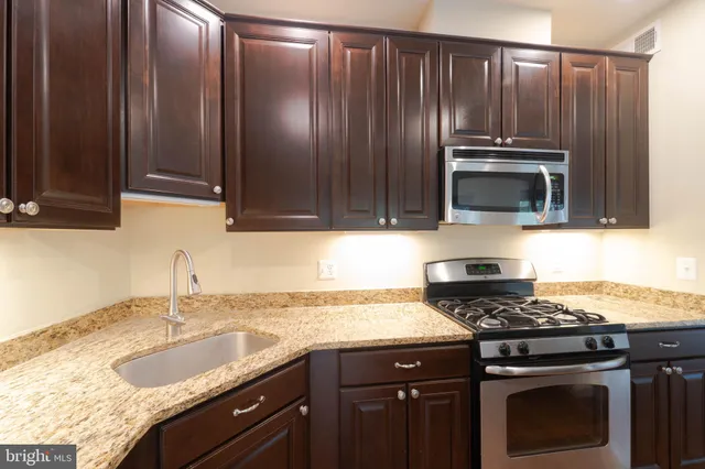 a kitchen with kitchen island granite countertop a sink stove and refrigerator