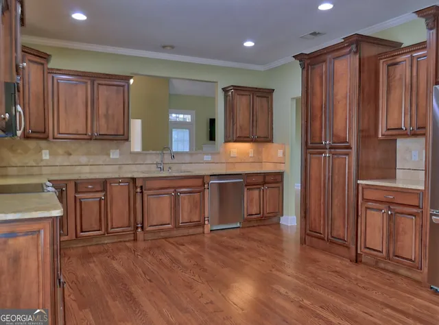 a kitchen with stainless steel appliances granite countertop wooden floors wooden cabinets a sink and dishwasher
