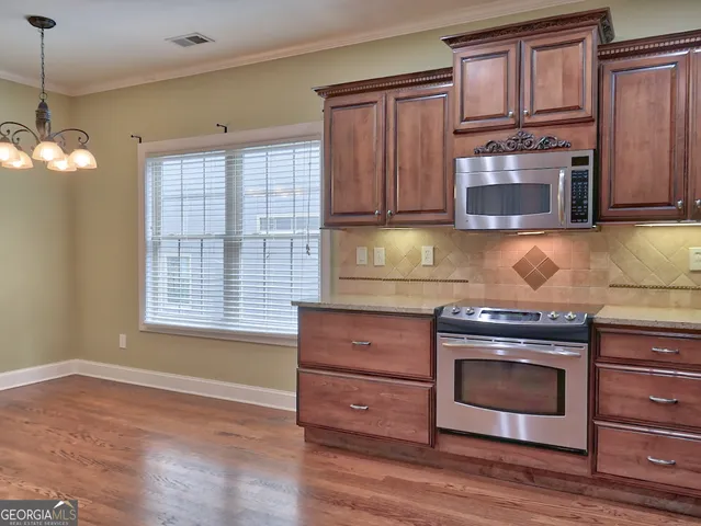 a kitchen with granite countertop wooden cabinets stainless steel appliances and a window